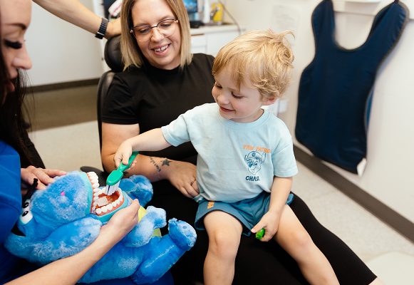 A child practices brushing on a stuffed animal with a Norwood Dental Centre hygienist